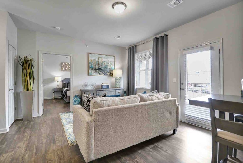 Living Room couch, hardwood floors, gray curtains with bedroom door at Multifamily investment property
